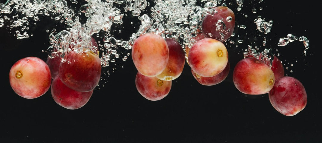 Red grapes splashing into water